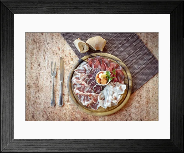 Framed Print : Wood chopping board with mixed italian cold cuts appetizer and cutlery from above Framed Print : Wood chopping board with mixed italian cold cuts appetizer and cutlery from above