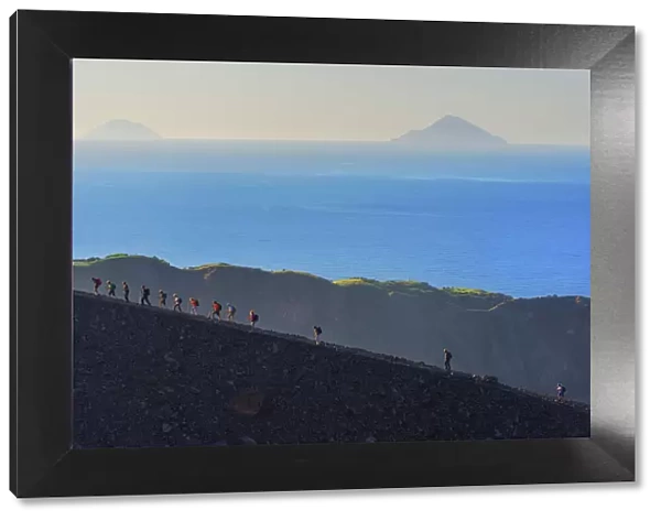 Hikers walking around Gran Crater rim, Vulcano Island, Aeolian Islands, Sicily, Italy