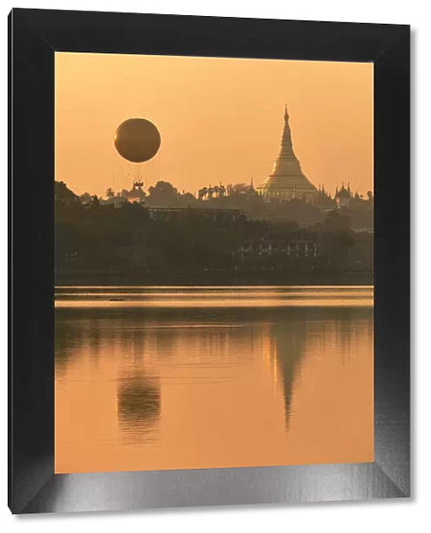 The golden stupa of the Shwedagon Pagoda and the Mingalarbar hot air baloon reflected in