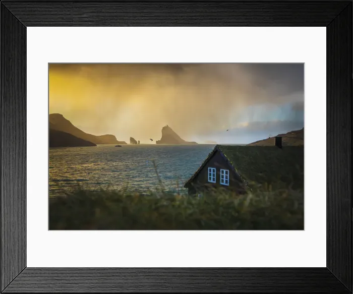 Framed Print : A snow shower is moving towards the turf houses in the village of Bour. In the background Drangarnir and Tindholmur are illuminated by the low sun. Vagar, Faroe Islands Framed Print : A snow shower is moving towards the turf houses in the village of Bour. In the background Drangarnir and Tindholmur are illuminated by the low sun. Vagar, Faroe Islands