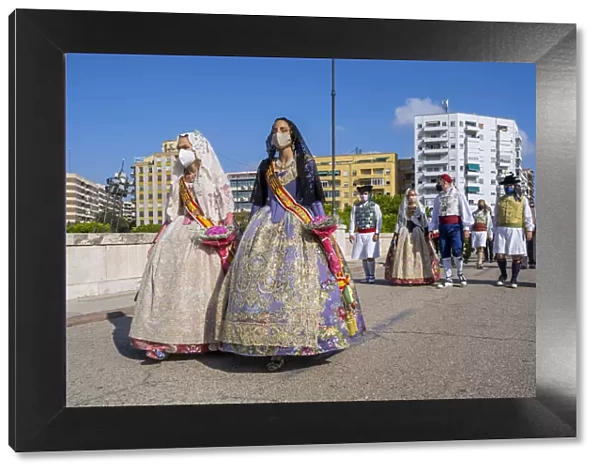 Falleras women wearing traditional dress and surgical mask in a parade during the 2021