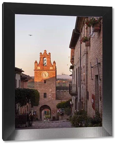 The clock tower of the medieval village of Gradara at sunrise with the hills in