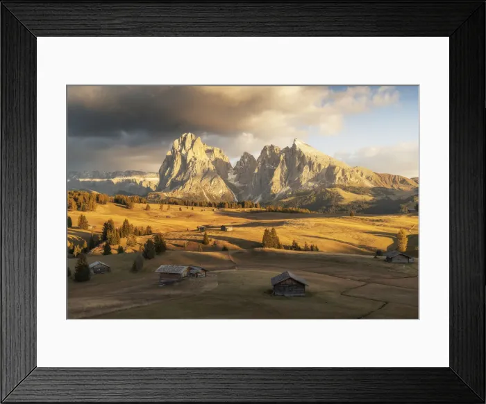Framed Print : Some old cabins lost in the meadows of the Alpe di Siusi (Seiser Alm) during an early autumn sunset, with the Sassolungo and Sassopiatto in the background. Dolomites, Italy