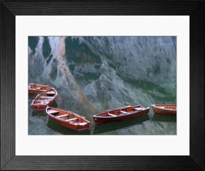 Framed Print : Row boats floating in the Braies lake on a calm morning, with the mountains reflecting in the water. Dolomites, Italy