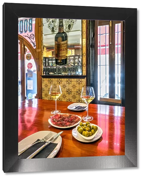 Glasses of white wine with olives and cecina dried meat served in a tapas bar of Valencia, Spain