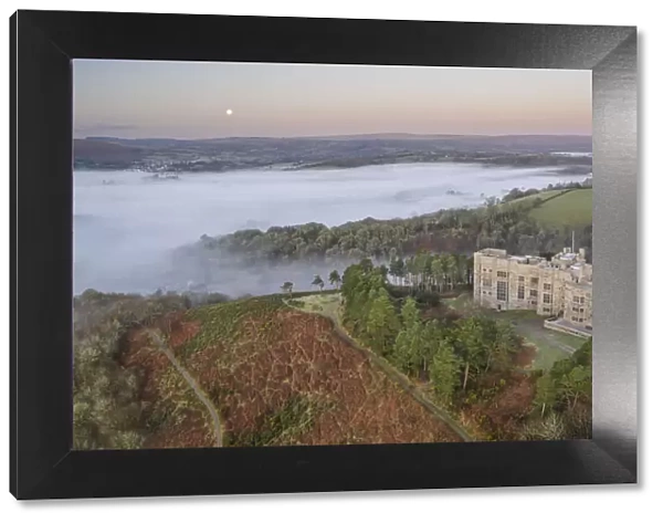 Aerial view of Castle Drogo at dawn on a misty winter morning, Dartmoor National Park, Devon, England. Winter (March) 2022