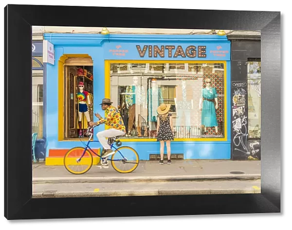 A woman looking in a vintage shop and a man riding his bike, Notting hill, London, England, Uk