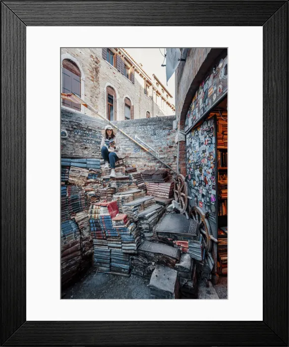 Framed Print : Venice, Veneto, Italy. Woman sitting on books at ancient Acqua Alta Library (MR) Framed Print : Venice, Veneto, Italy. Woman sitting on books at ancient Acqua Alta Library (MR)