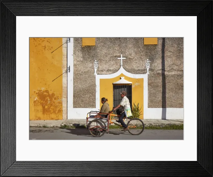 Framed Print : Locals on a tricycle passing by the front facade of a colonial house in Izamal, Yucatan, Mexico Framed Print : Locals on a tricycle passing by the front facade of a colonial house in Izamal, Yucatan, Mexico