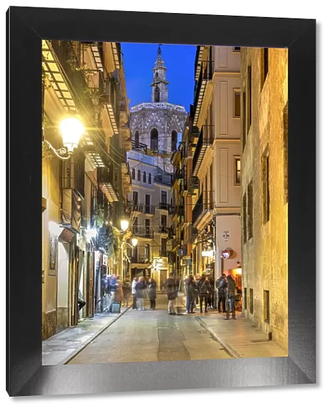 Night view of an old towns street with Miguelete Tower in the background, Valencia, Spain
