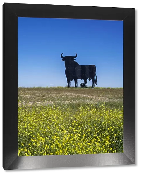 Scenic springtime landscape with a silhouetted image of an Osborne bull billboard in rural Castilla-La Mancha, Spain