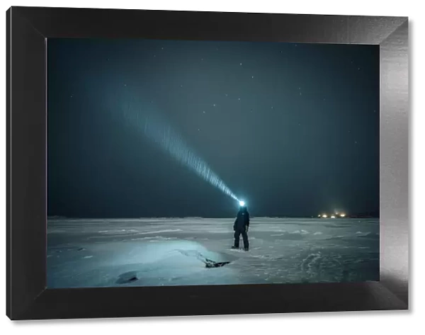 Man exploring the sky at night on a iced lake on the arctic circle, Abisko, Sweden
