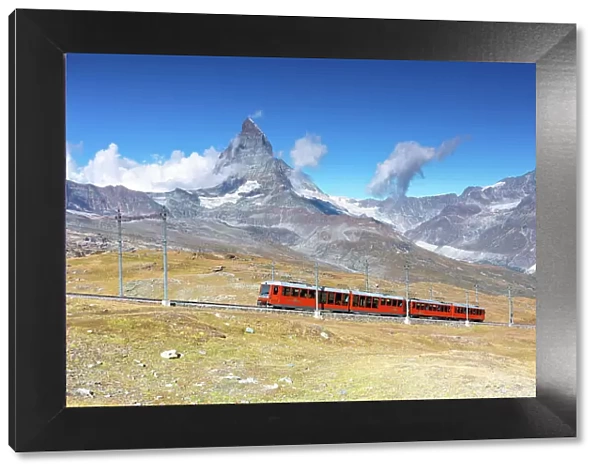 the iconic red train over the Gornegrat railway, with the Matterhorn mountain in background, Zermatt, Canton of Valais, Switzerland