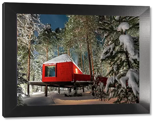 Red hut in the winter forest covered with snow, accommodation for tourists of the Tree hotel, Harads, Lapland, Sweden