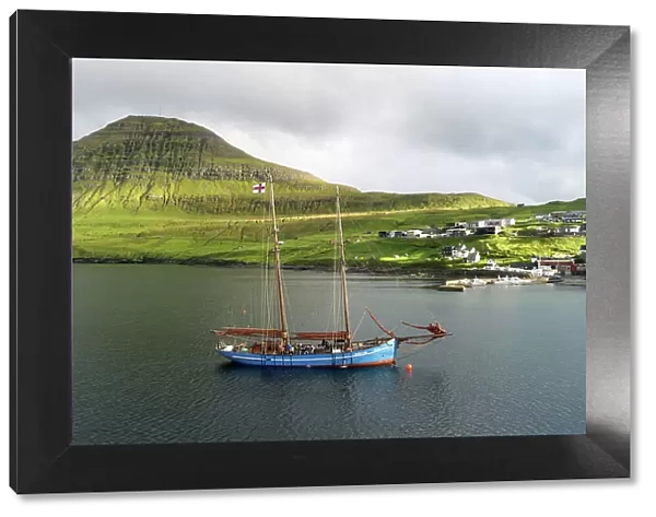 The Faroese-built wooden sailship Norðlysið (The Nordic Lights) sailing in fron of the village of Syðrugota. Island of Eysturoy. Faroe Islands