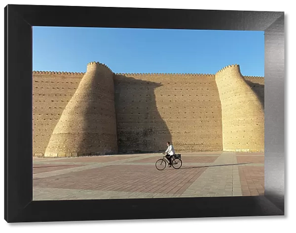 Uzbekistan, Bukhara, UNESCO world heritage site, Ark Fortress, a man cycles past the city walls