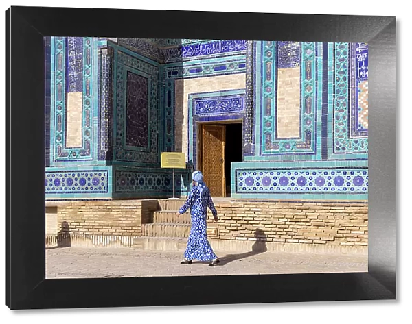 Uzbekistan, Samarkand, Shah-i-Zinda, Tomb Street of 11 Mausoleums, a local woman walks past one of the mausoleums