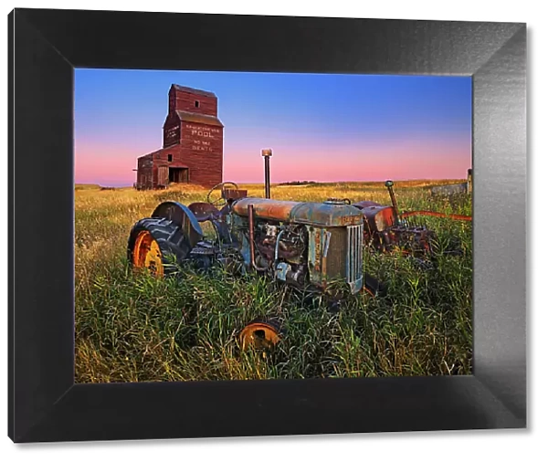 Grain elevator with old tractor at dawn Bents Saskatchewan, Canada