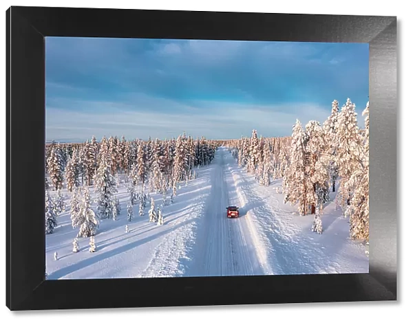 High angle car driving on an icy road among trees covered with snow, Kangos, Lapland, Sweden