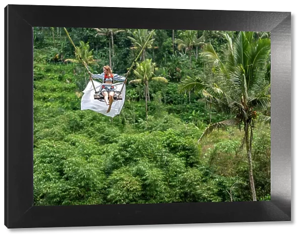 Tourist woman swinging over the Balinese tropical forest, Ubud, Indonesia