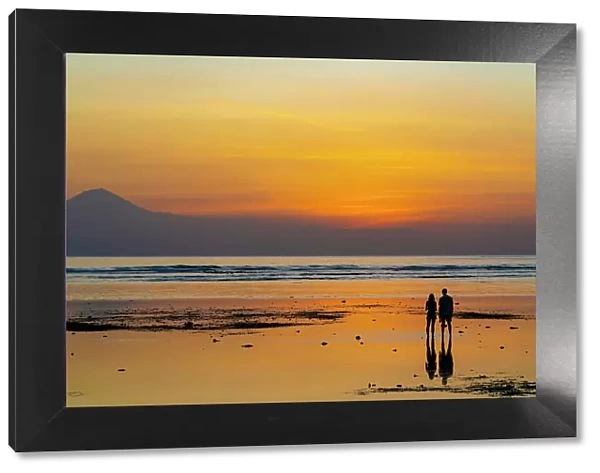 Couple watching sunset on low tide, Gili Trawangan, Lombok, Indonesia
