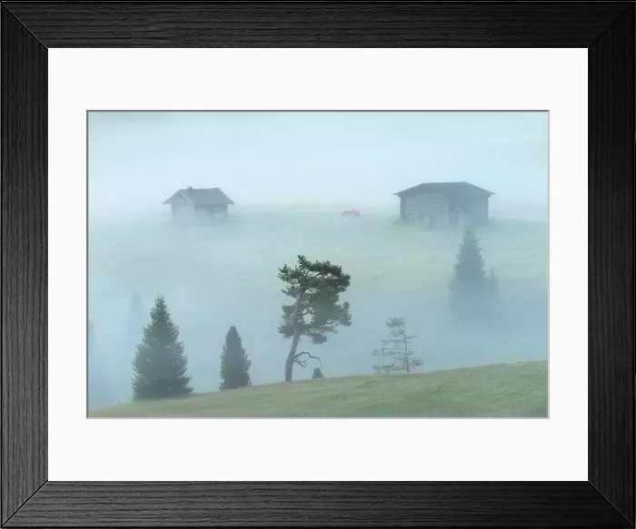 Framed Print : Two wooden cabins appearing from the thick morning fog at the Alpe di Siusi. Dolomites, Italy
