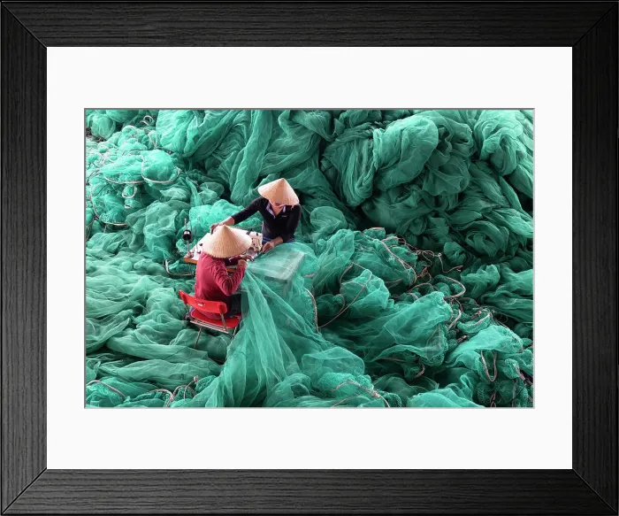 Framed Print : Vietnam, Cam Ranh, two men repair green fishing nets using a sewing machine