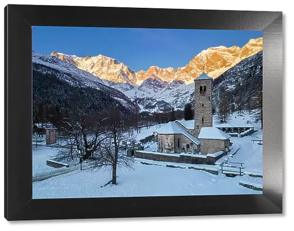 Sunrise in front of Monte Rosa from the old church of Macugnaga in winter. Valle Anzasca, Ossola, province of Verbania, Piedmont, italian alps, Italy