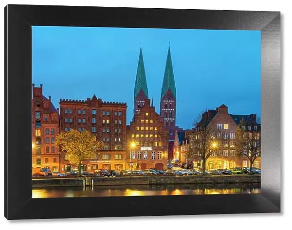 Houses on riverfront of Trave river with towers of St. Marienkirche church in background at twilight, Lubeck, UNESCO, Schleswig-Holstein, Germany