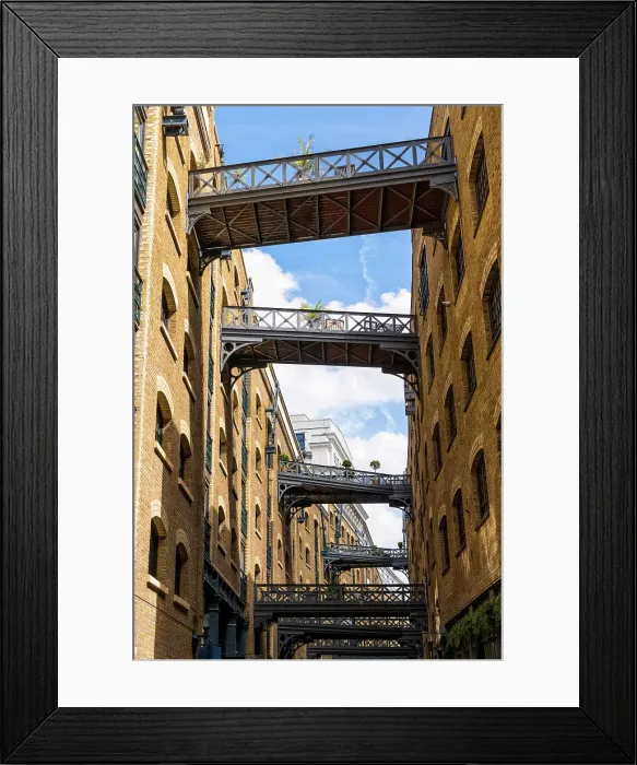 Framed Print : The cobbled street Shad Thames, behind Butler's Wharf on the River Thames, known for its renovated warehouse /  apartment and restored overhead bridges and walkways, London, England