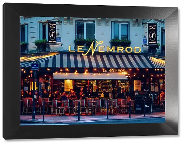 Le Nemrod illuminated after sunset. Typical Cafe Restaurant in Paris, France
