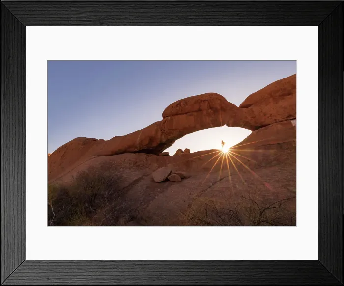 Framed Print : Namibia, a woman hiking to the top of Spitzkoppe natural rock arch and looking at the sun setting MR