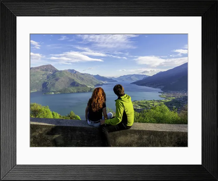 Framed Print : two turist admire lake Como, sitting on the wall of santa croce church, Gravedona ed uniti, Como district, Lombardy, Italy Framed Print : two turist admire lake Como, sitting on the wall of santa croce church, Gravedona ed uniti, Como district, Lombardy, Italy