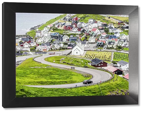 High angle view of car driving on winding road to the iconic Eidi village, Eysturoy Island, Faroe Islands