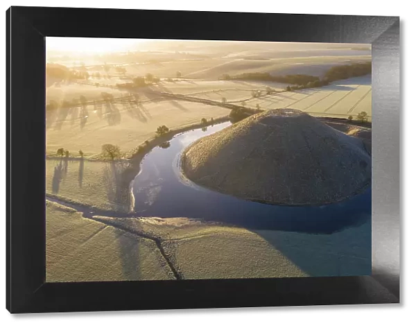 Aerial view of a flooded Silbury Hill on a frosty winter morning, Avebury, Wiltshire, England. Winter (February) 2023