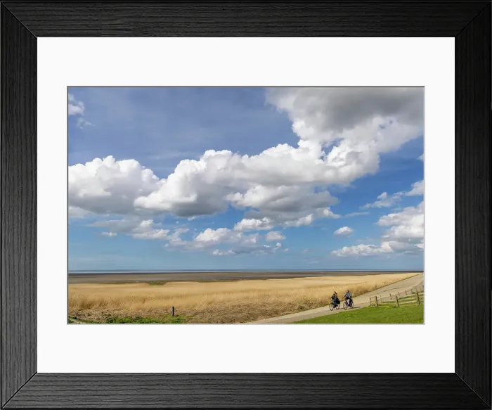 Framed Print : A couple cycle along a section of dyke along the Wadden sea in NW Friesland, Holland, Netherlands Framed Print : A couple cycle along a section of dyke along the Wadden sea in NW Friesland, Holland, Netherlands