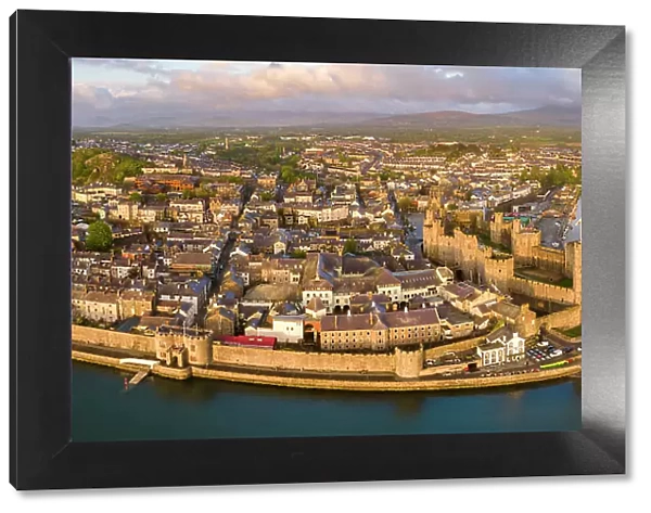 Aerial view of Caernarfon Castle and town on a sunny spring evening, Caernarfon, North Wales, UK. Spring (May) 2023