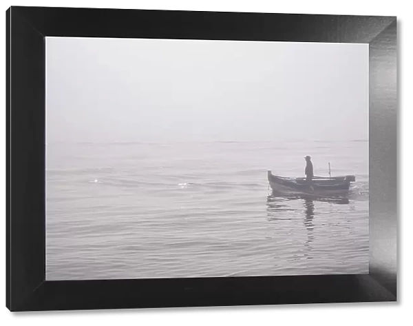 Fishing boat in a foggy morning coming from the sea. Setubal, Portugal