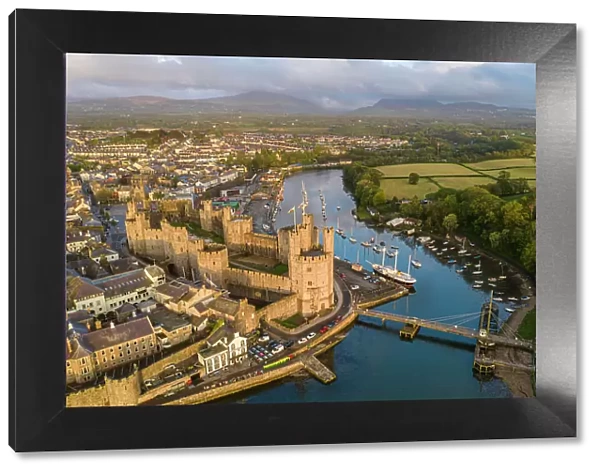 Aerial view of Caernarfon Castle and town in gorgeous evening sunlight, Caernarfon, Wales, UK. Spring (May) 2023
