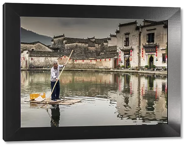 Man collecting rubbish in pond, Hongcun, China