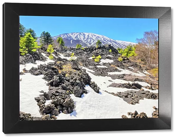 View of lava fields and snow-capped peaks in the distance, Etna, Sicily, Italy