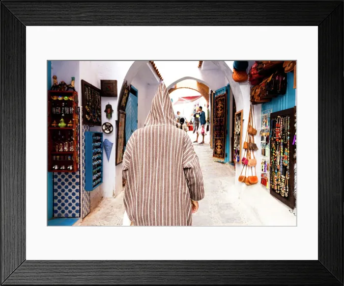 Framed Print : Man with traditional Djellaba looking at the gift shops in the street markets of Chefchaouen, Morocco
