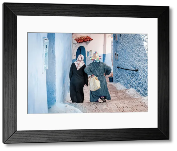 Framed Print : Senior women with hijab walking along the blue buildings of medina, Chefchaouen, Morocco