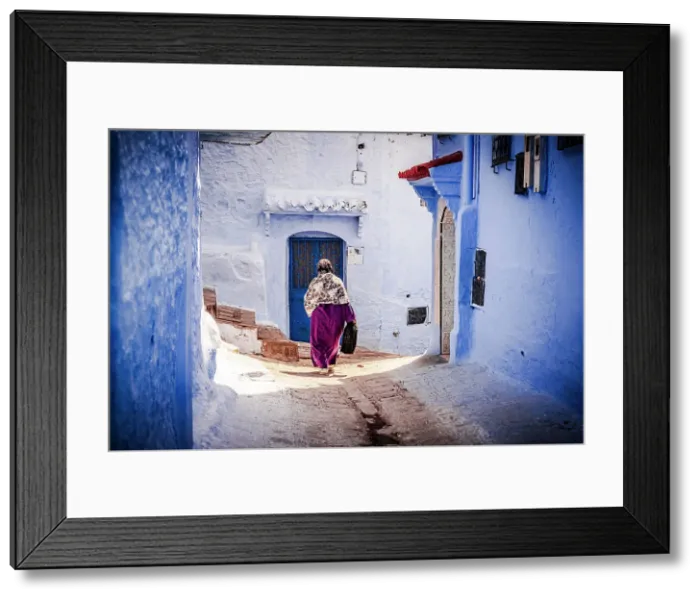 Framed Print : Senior woman with hijab walking among blue buildings of medina, Chefchaouen, Morocco Framed Print : Senior woman with hijab walking among blue buildings of medina, Chefchaouen, Morocco