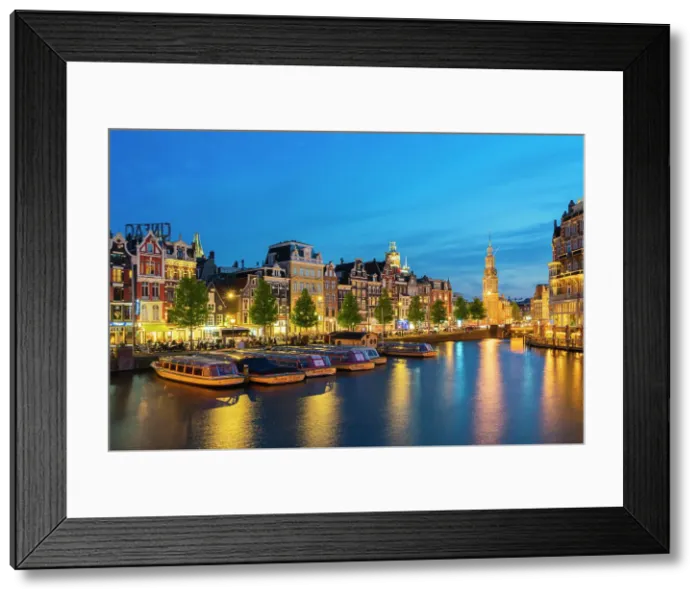 Framed Print : Boats moored along illuminated street on Amstel River and Munttoren tower at twilight, Amsterdam, Netherlands Framed Print : Boats moored along illuminated street on Amstel River and Munttoren tower at twilight, Amsterdam, Netherlands