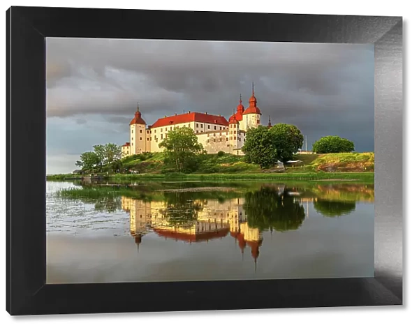 Baroque Lacko castle and its reflection in the water of Vanem lake at sunset, Kallandso island, Lidkoping municipality, Gotaland, Sweden