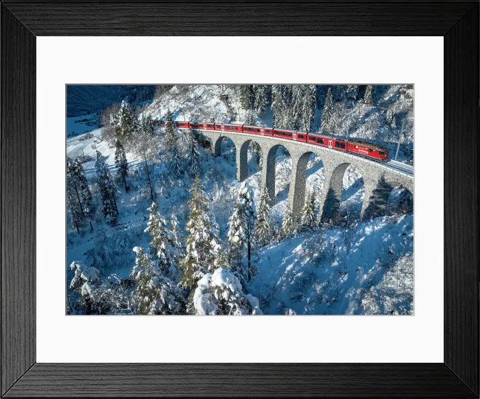 Framed Print : Sunlight over the famous red train traveling across the winter snowy forest in the Swiss Alps, Graubunden canton, Switzerland Framed Print : Sunlight over the famous red train traveling across the winter snowy forest in the Swiss Alps, Graubunden canton, Switzerland
