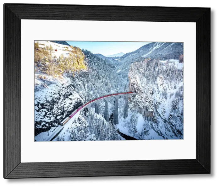 Framed Print : Aerial view of the Swiss red train crossing Landwasser viaduct in the cold winter, Filisur, Graubunden canton, Switzerland Framed Print : Aerial view of the Swiss red train crossing Landwasser viaduct in the cold winter, Filisur, Graubunden canton, Switzerland