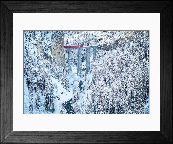 Framed Print : Swiss red train crossing Landwasser viaduct above a frozen river in the snowy landscape, Filisur, Graubunden canton, Switzerland