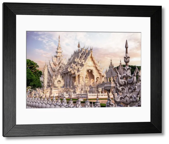 Framed Print : Surreal architecture and decorated fence at Wat Rong Khun (White Temple) at sunrise, Chiang Rai, Thailand Framed Print : Surreal architecture and decorated fence at Wat Rong Khun (White Temple) at sunrise, Chiang Rai, Thailand